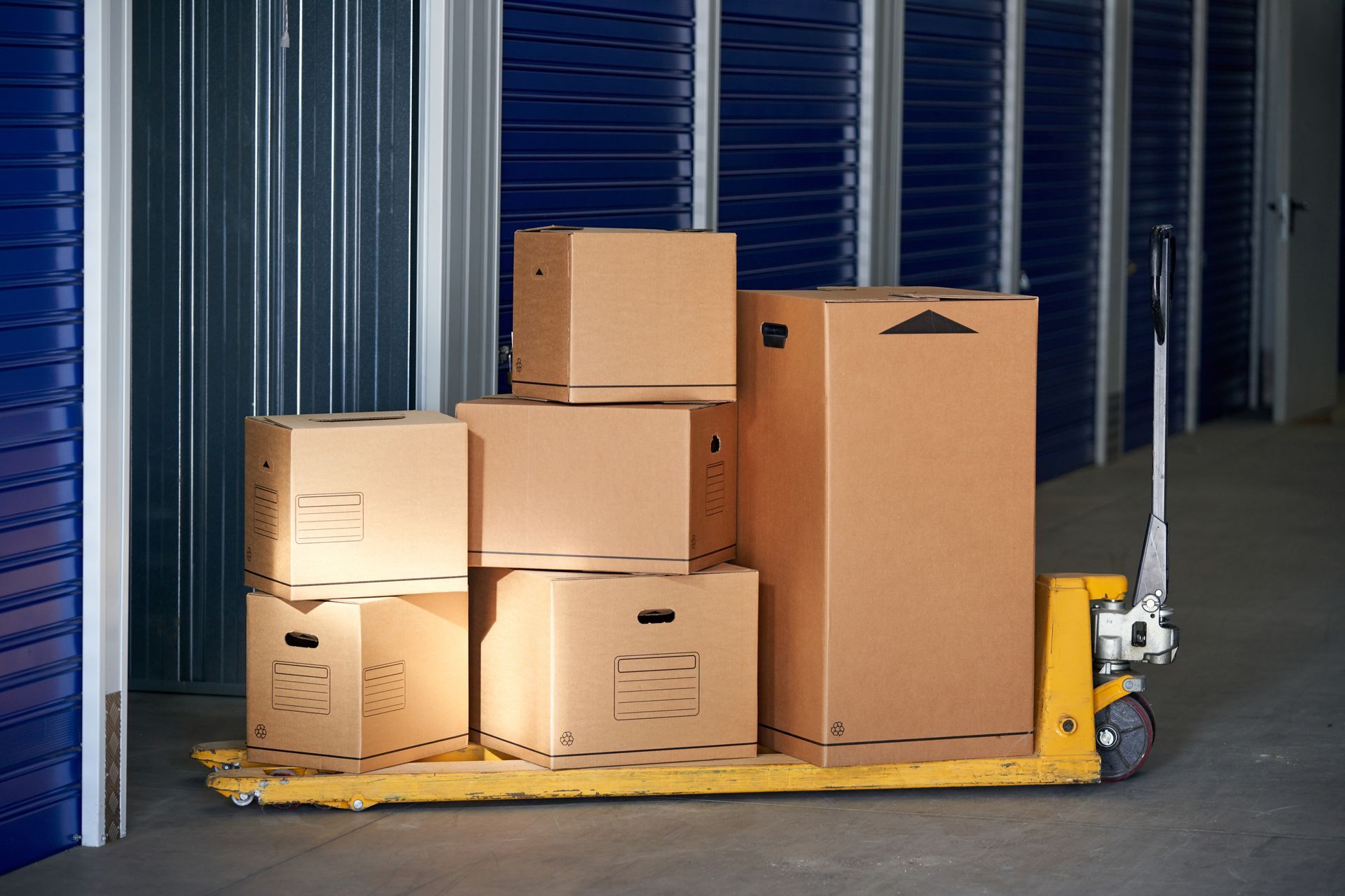 A yellow hand truck filled with cardboard boxes in a warehouse.