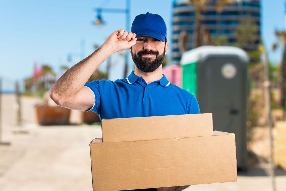 a delivery man is holding a cardboard box in his hand .