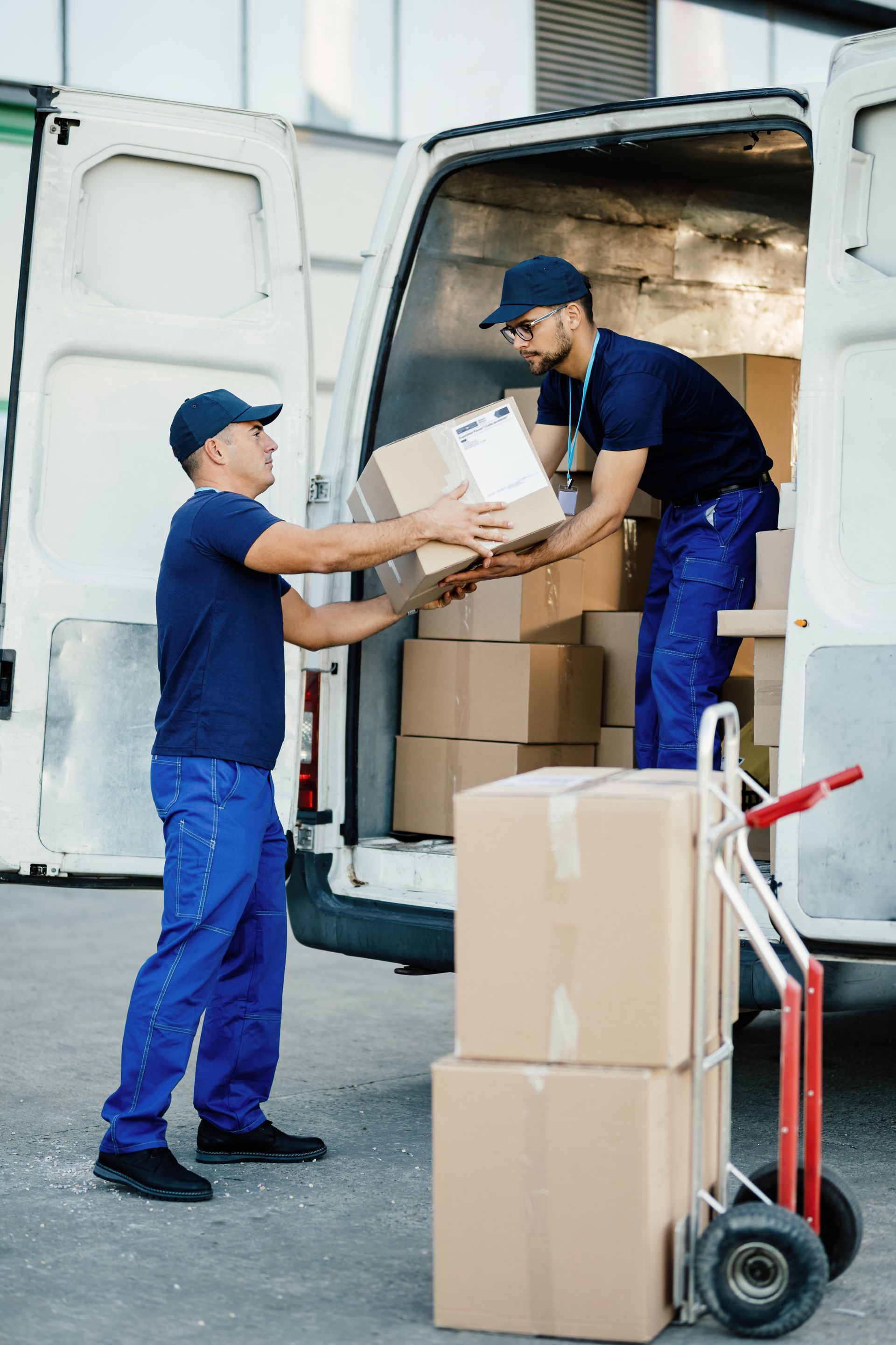 two workers are loading boxes into a van .