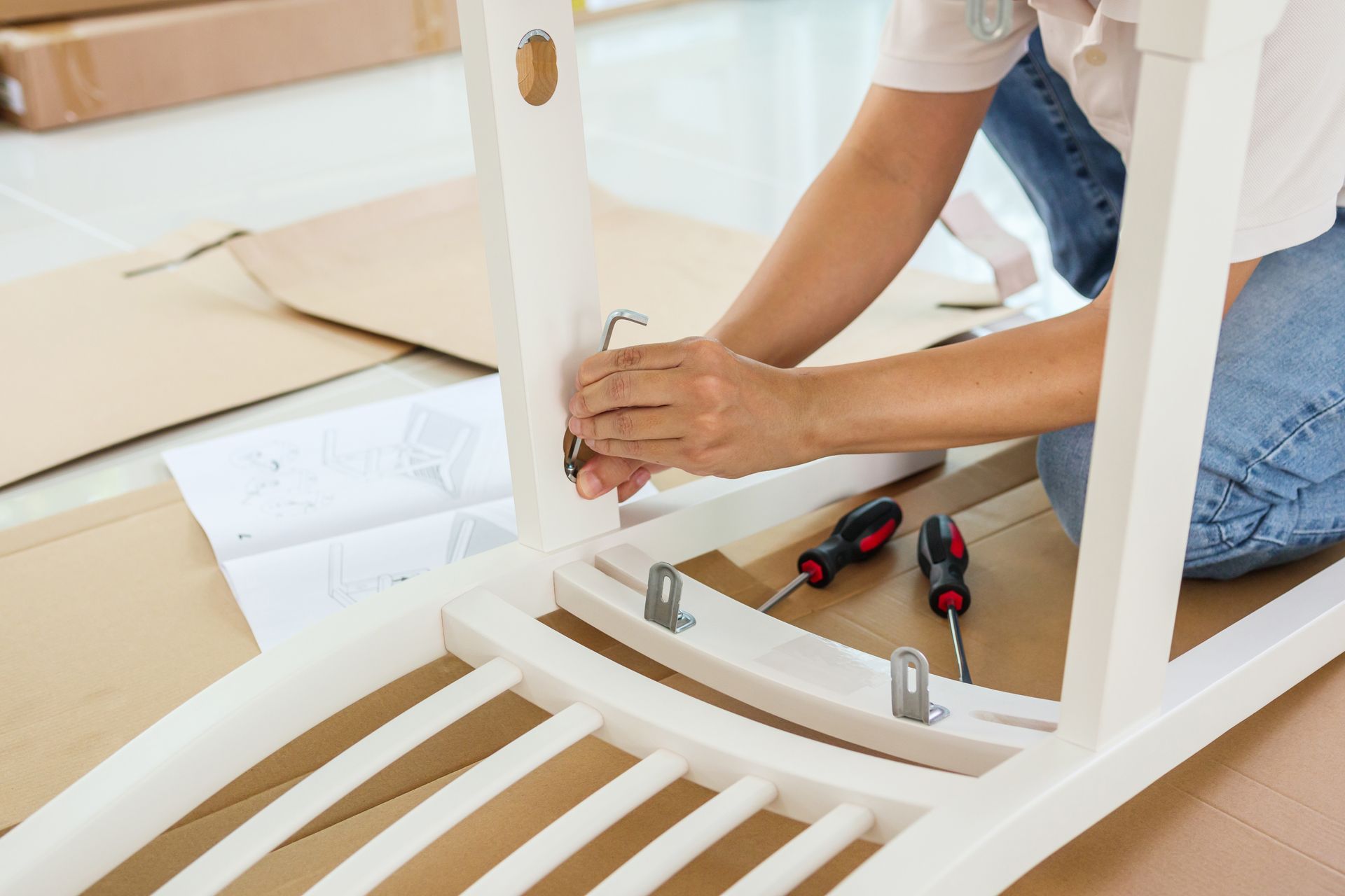 a woman is kneeling on the floor assembling a chair .