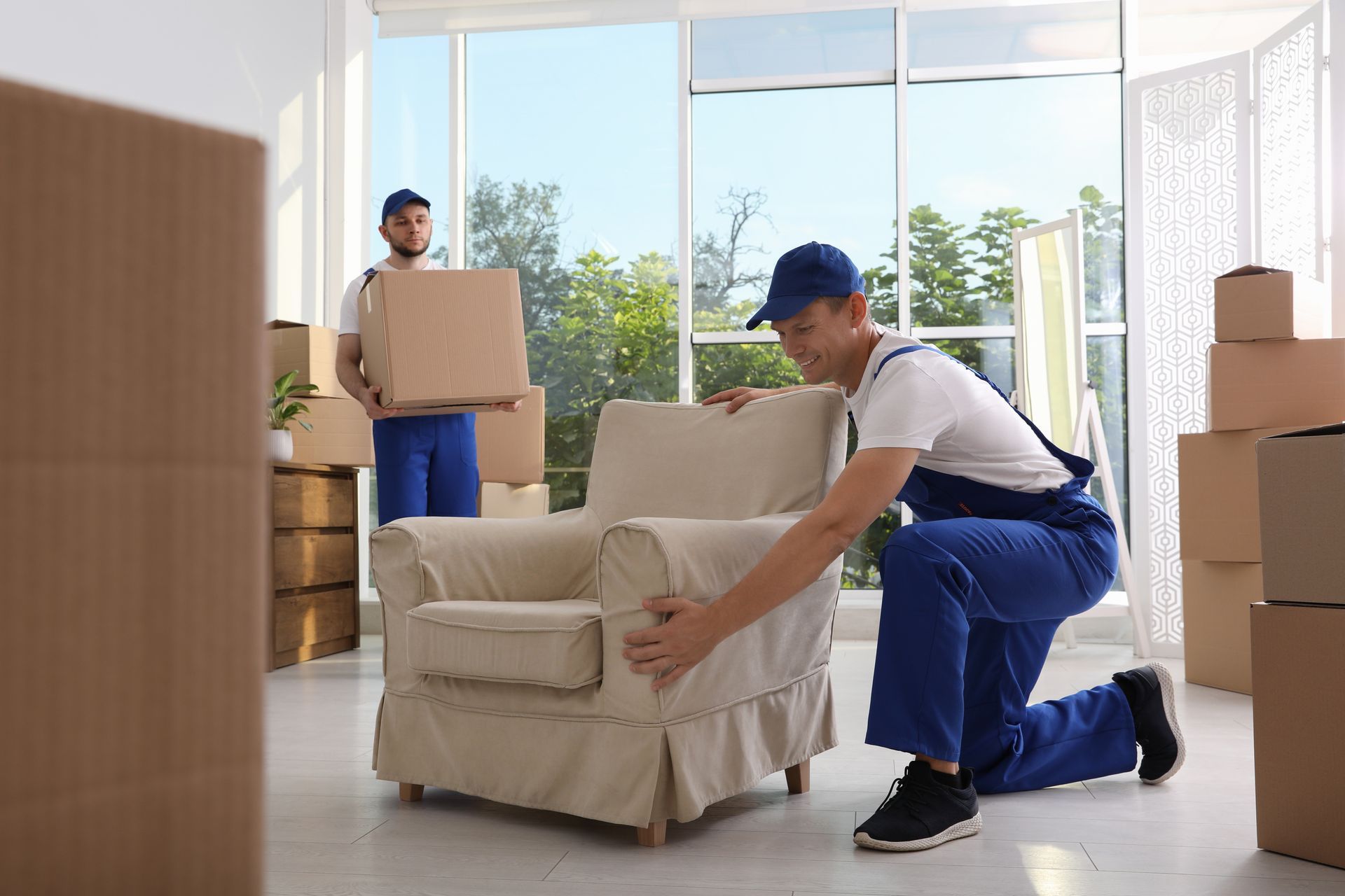 two men are moving boxes in a living room .
