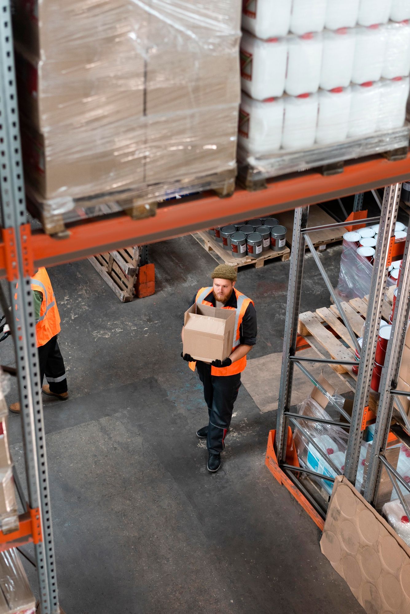 A man is carrying a box in a warehouse.