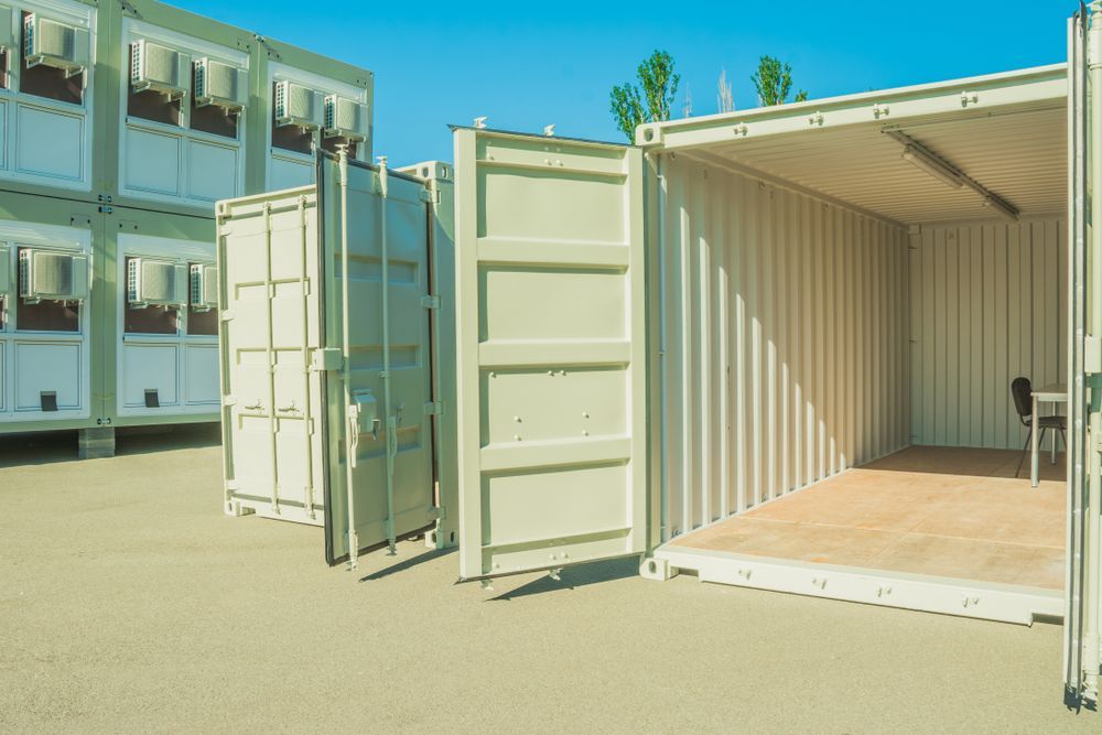 A row of shipping containers with their doors open in a parking lot.