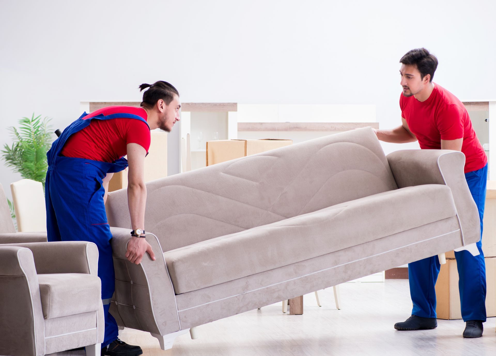 Two men are carrying a couch in a living room.