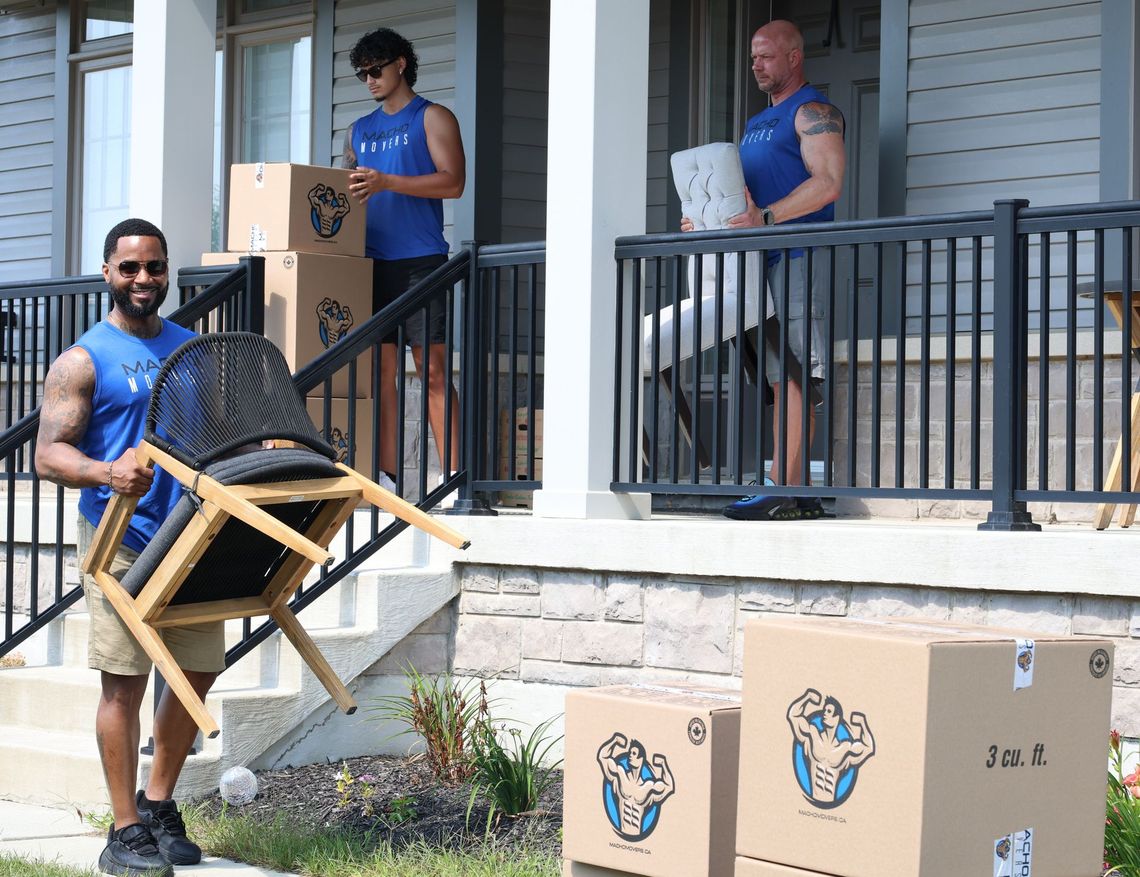 a group of movers are loading boxes into a van .