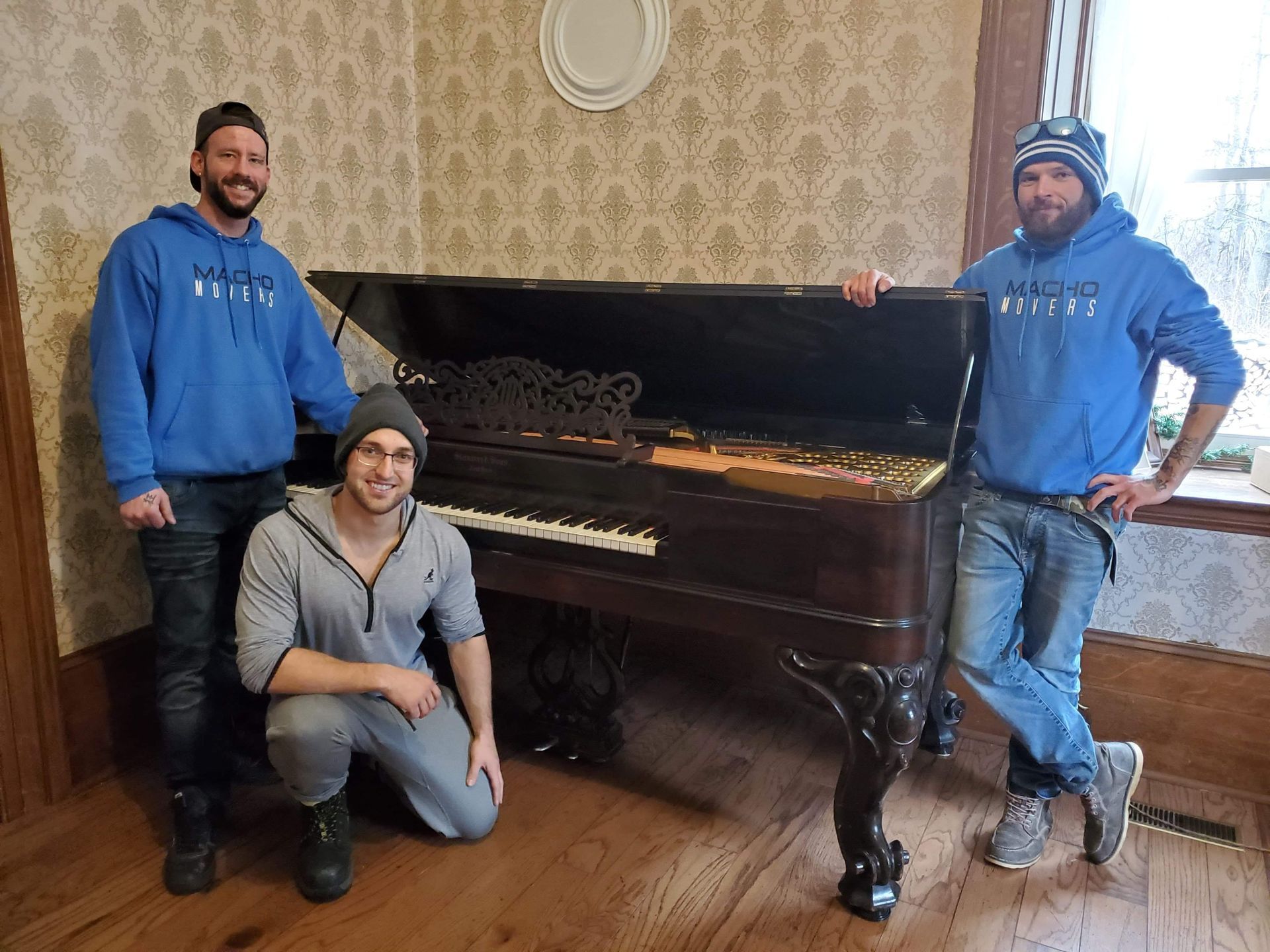 three men are standing next to a piano in a living room .