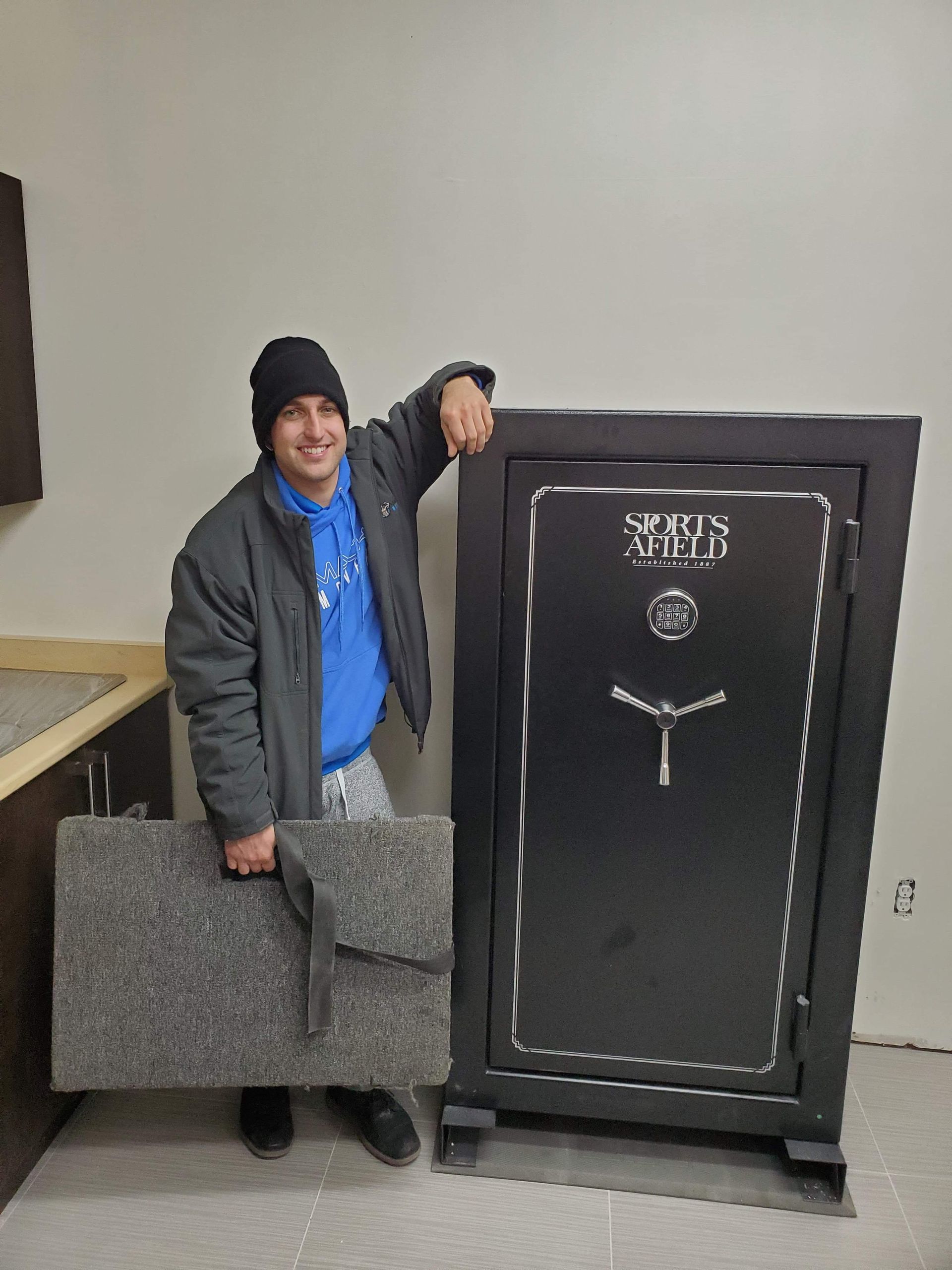 a man is holding a piece of carpet next to a safe .