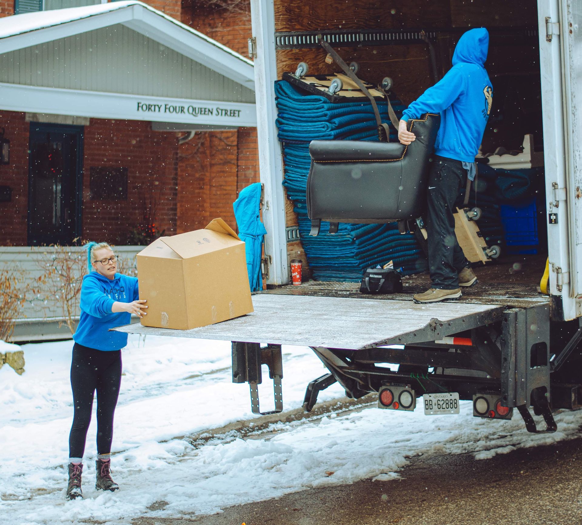 a man in a blue jacket is loading a chair into a truck