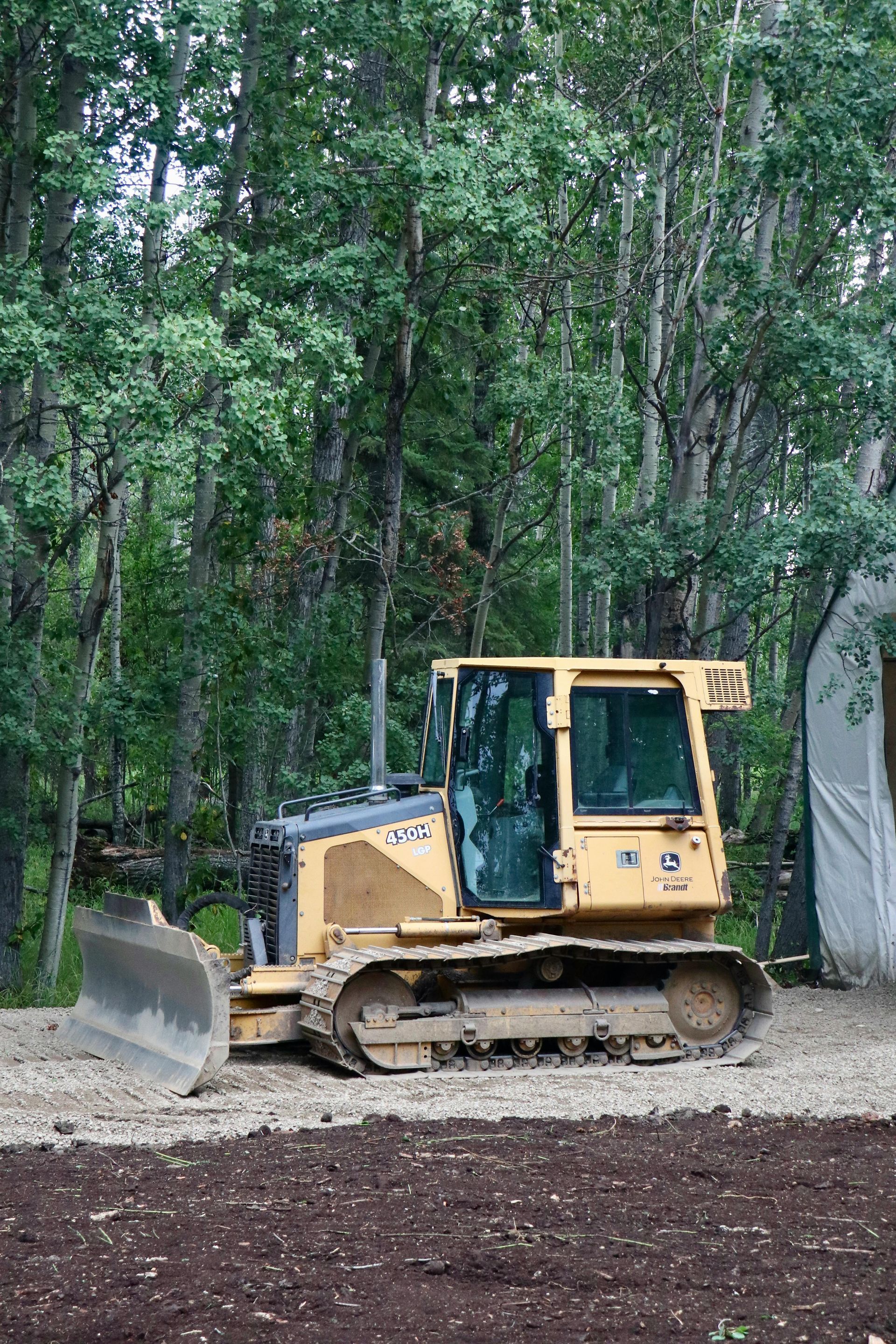 A bulldozer is parked in the middle of a forest.