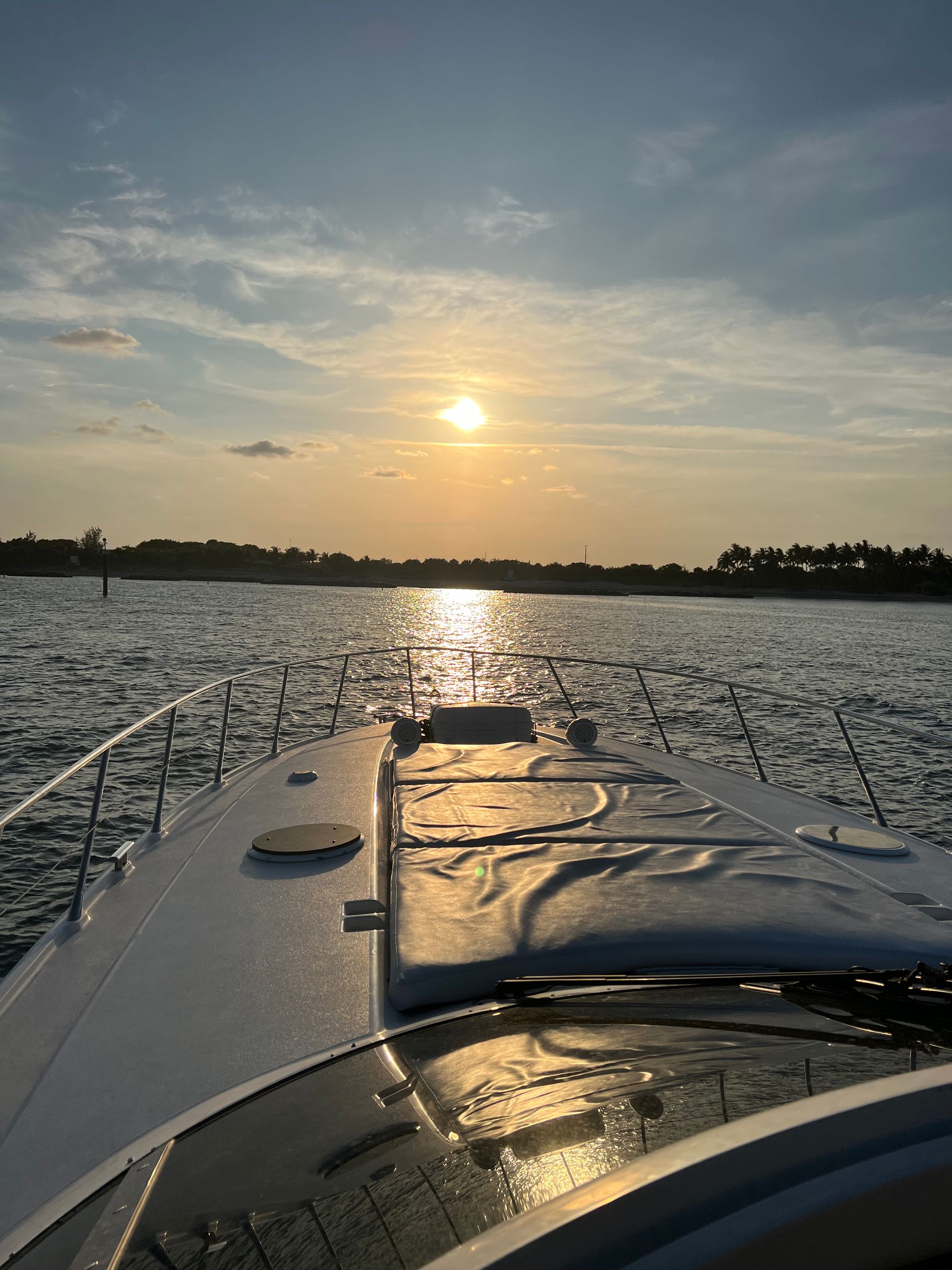 Boat sailing on water toward sunset, golden light reflecting.