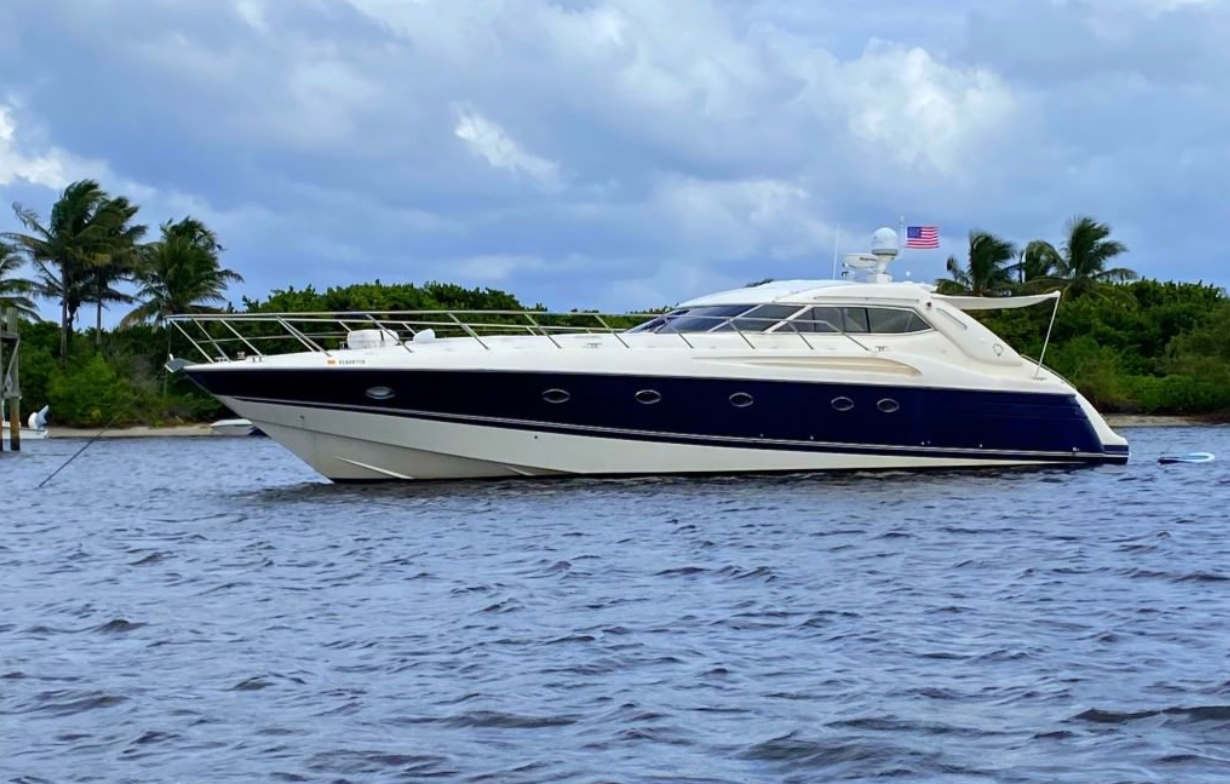 White and navy yacht on rippled water under cloudy sky.