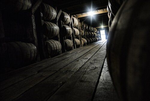 A wooden warehouse filled with lots of barrels of alcohol.
