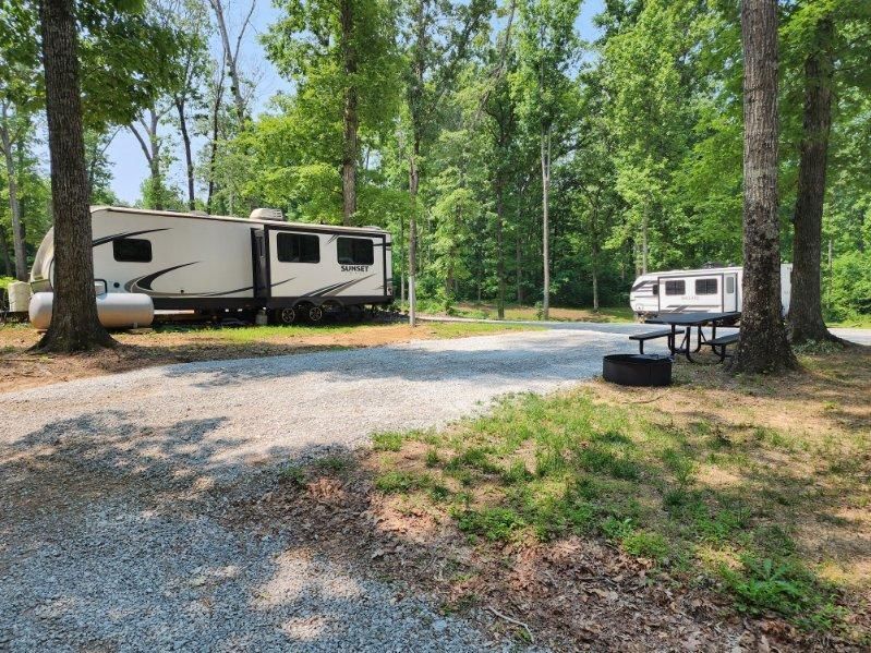 A rv is parked in a gravel lot next to a picnic table.
