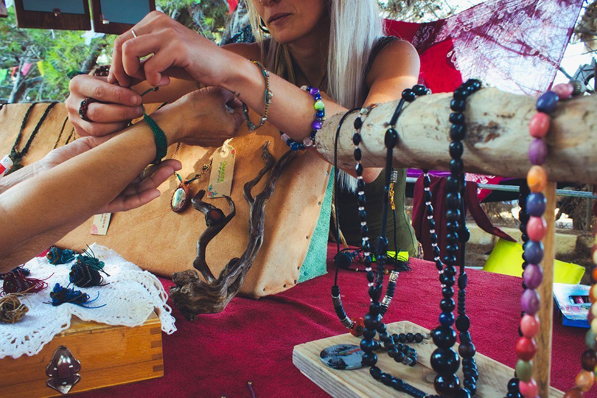 a woman is selling bracelets and necklaces at a market .