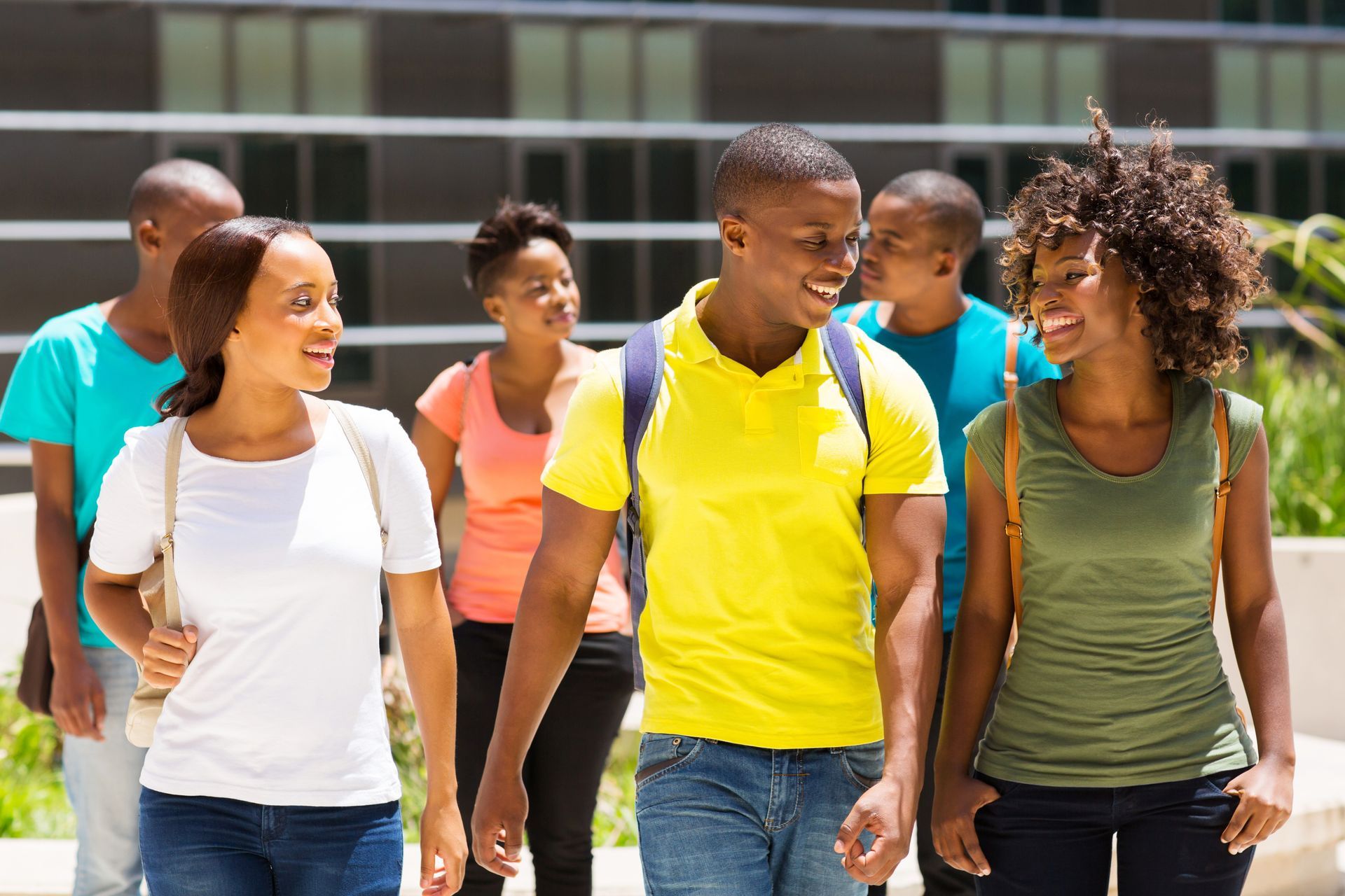 Group of students walking and talking on a sunny campus.