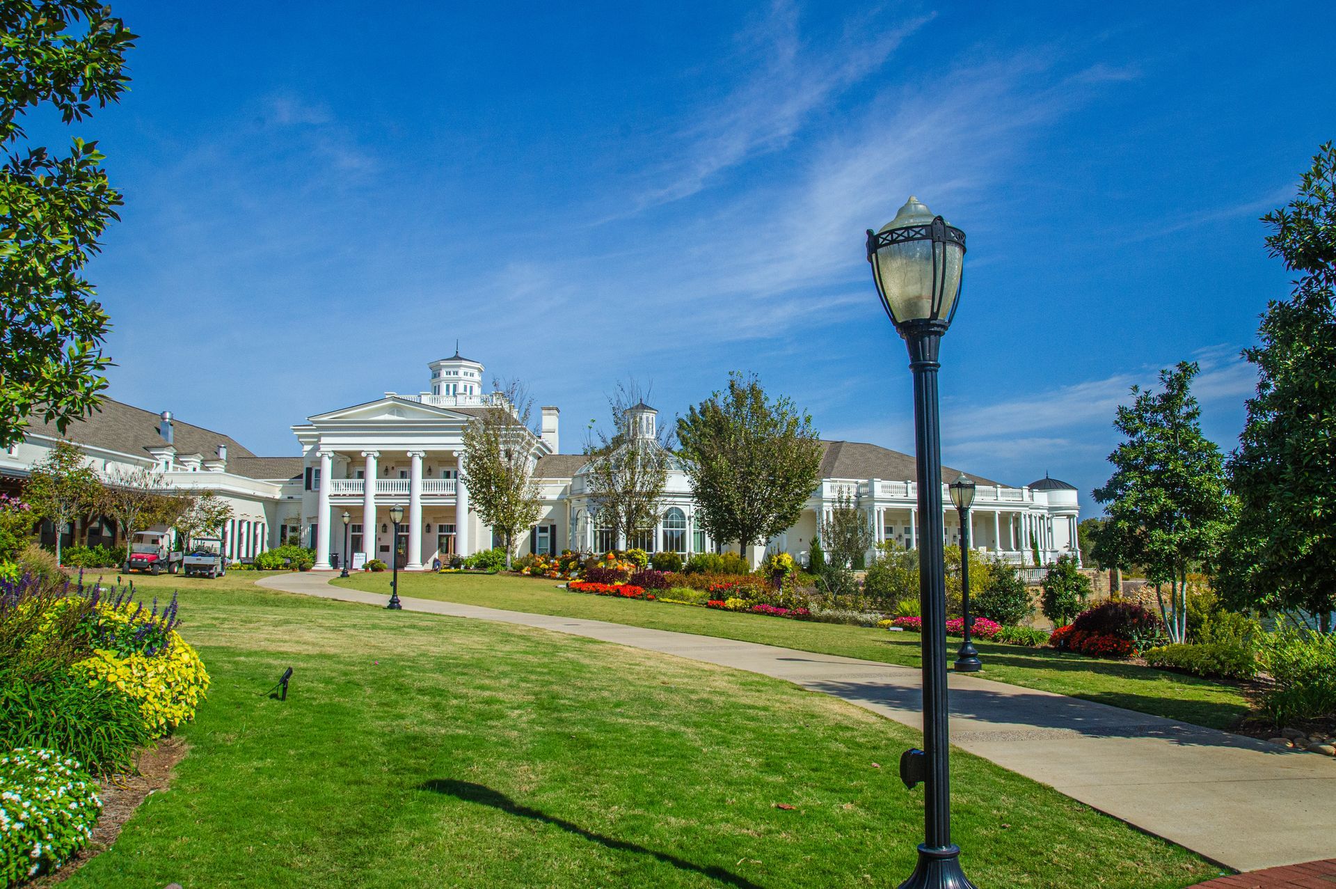A large white house is sitting in the middle of a lush green park.
