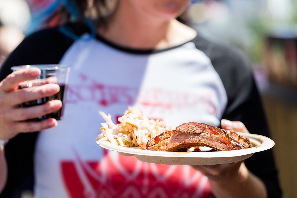 a woman is holding a plate of food and a glass of soda .