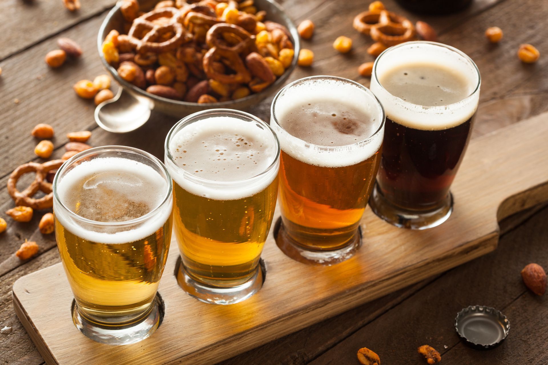 Four glasses of beer are sitting on a wooden tray.