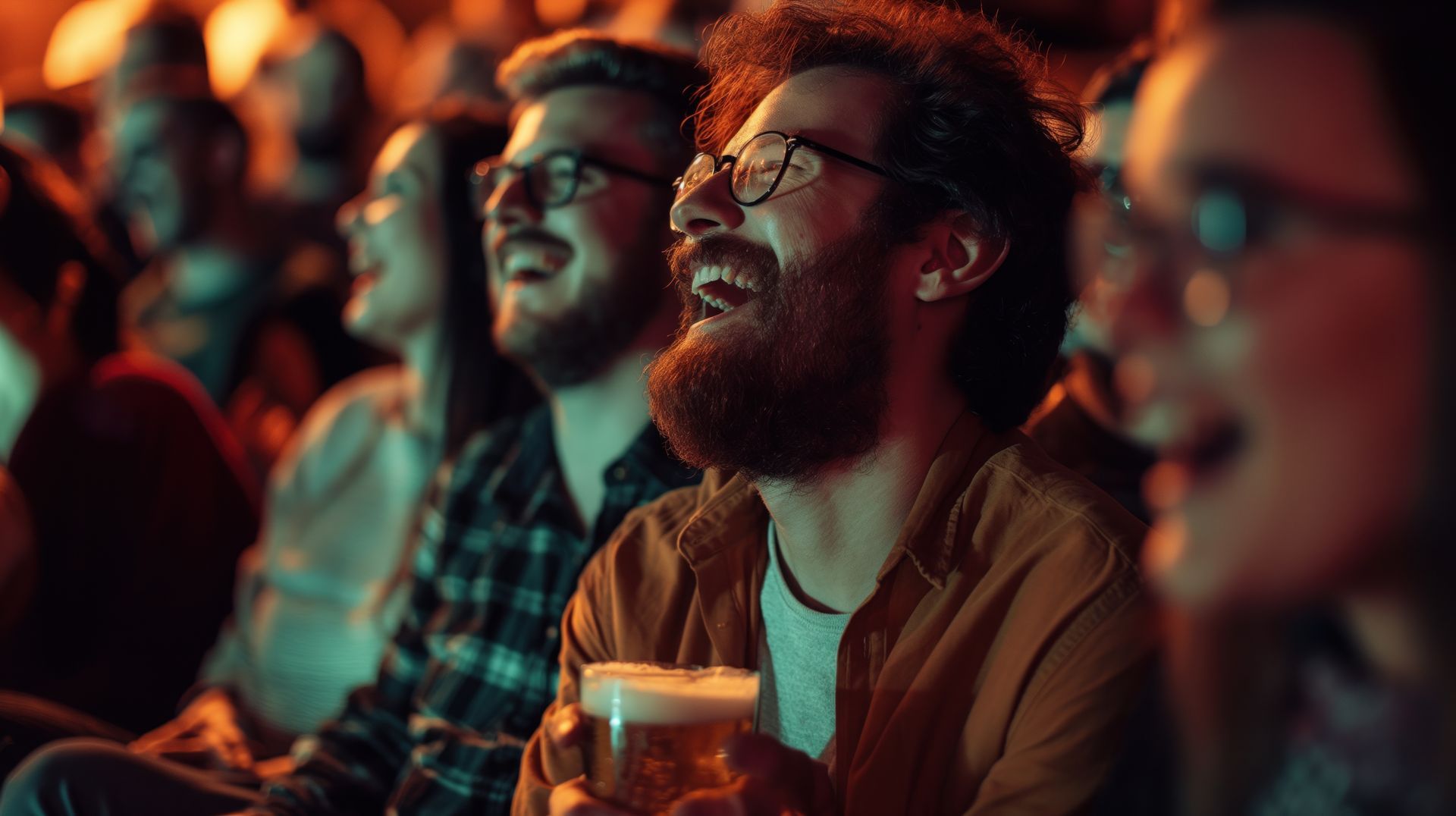 A group of people are sitting in a theater laughing and drinking beer.