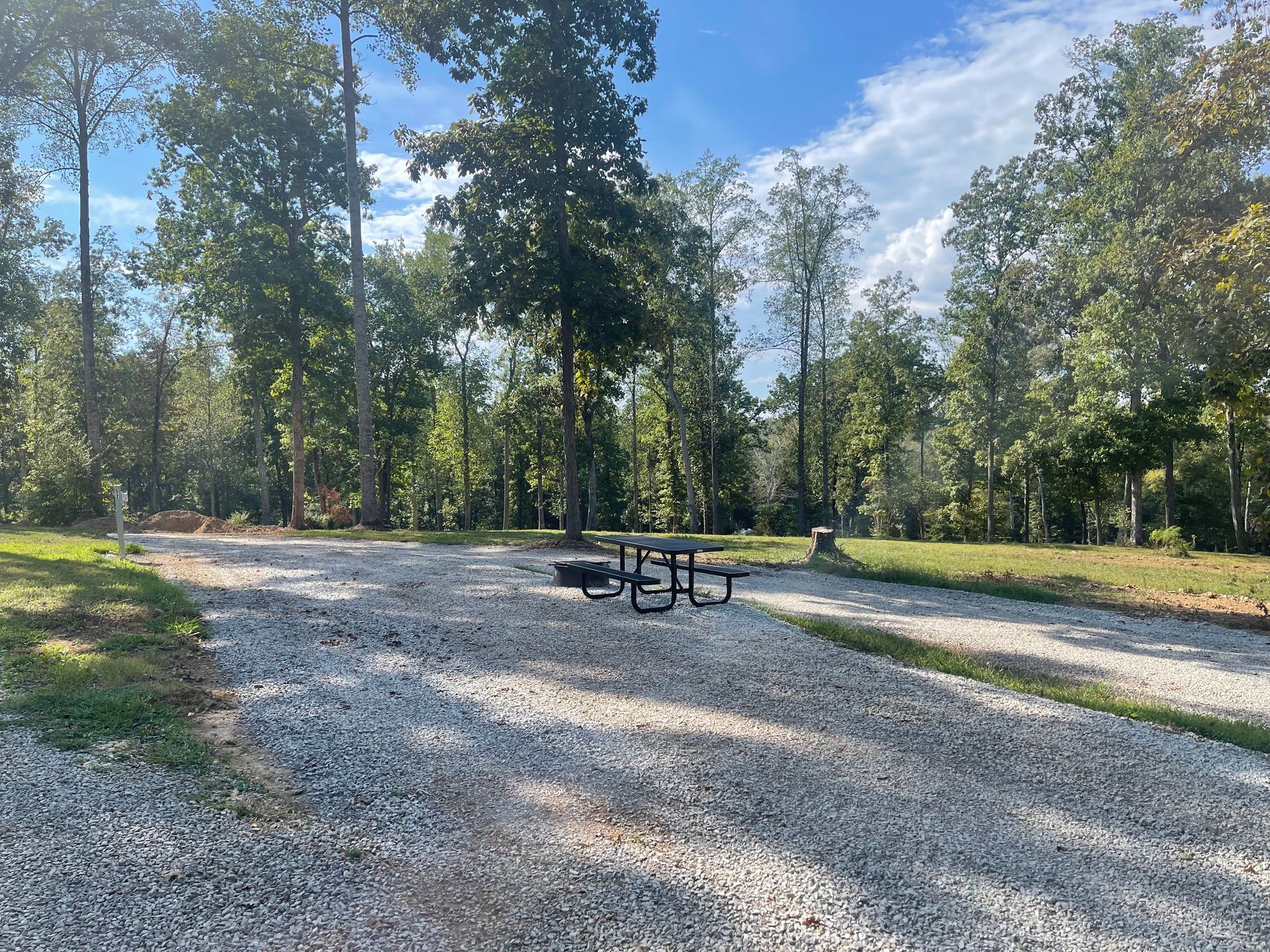 A gravel road with a picnic table in the middle of it.