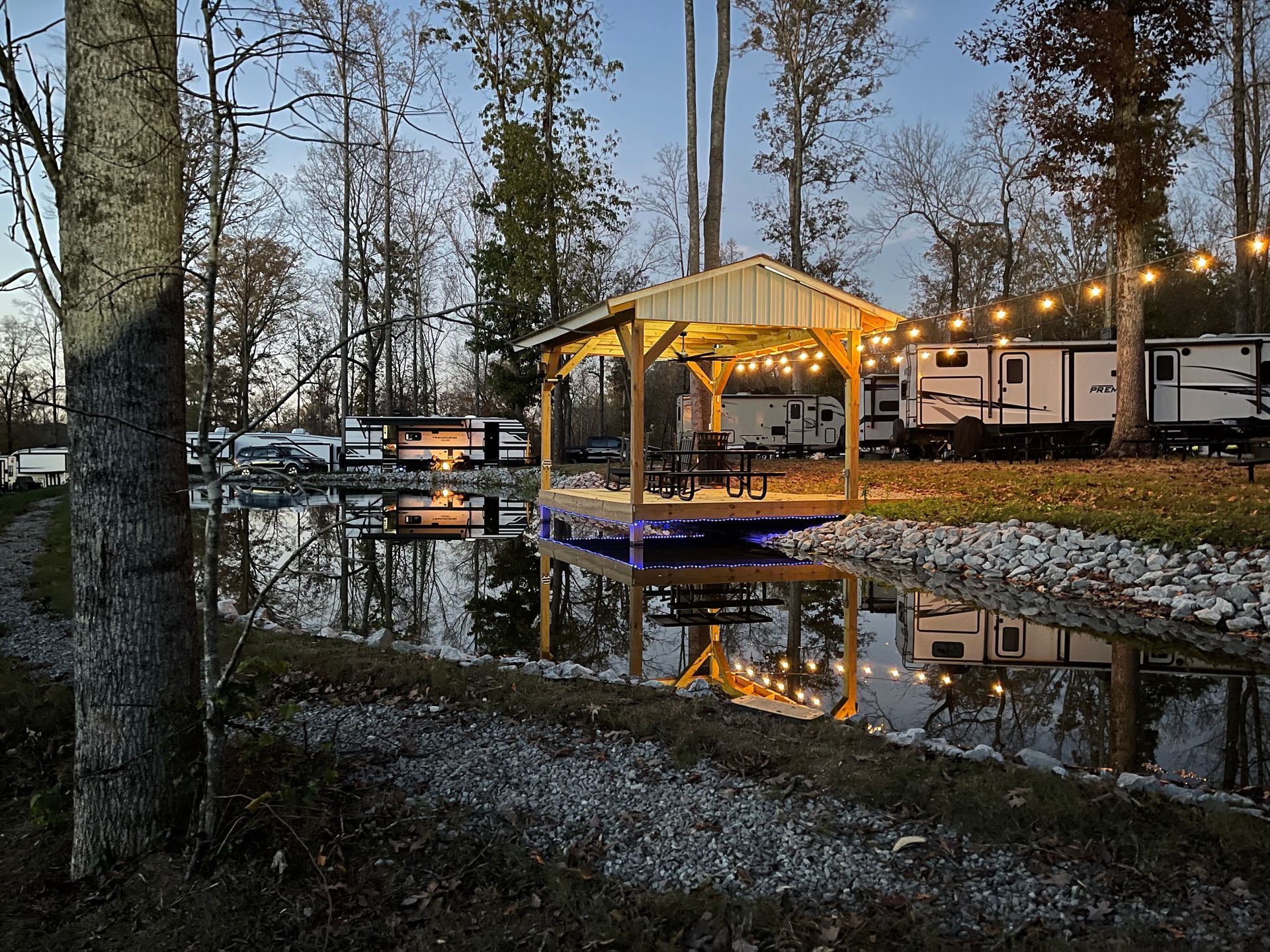A rv park with a gazebo and a boat in the water.