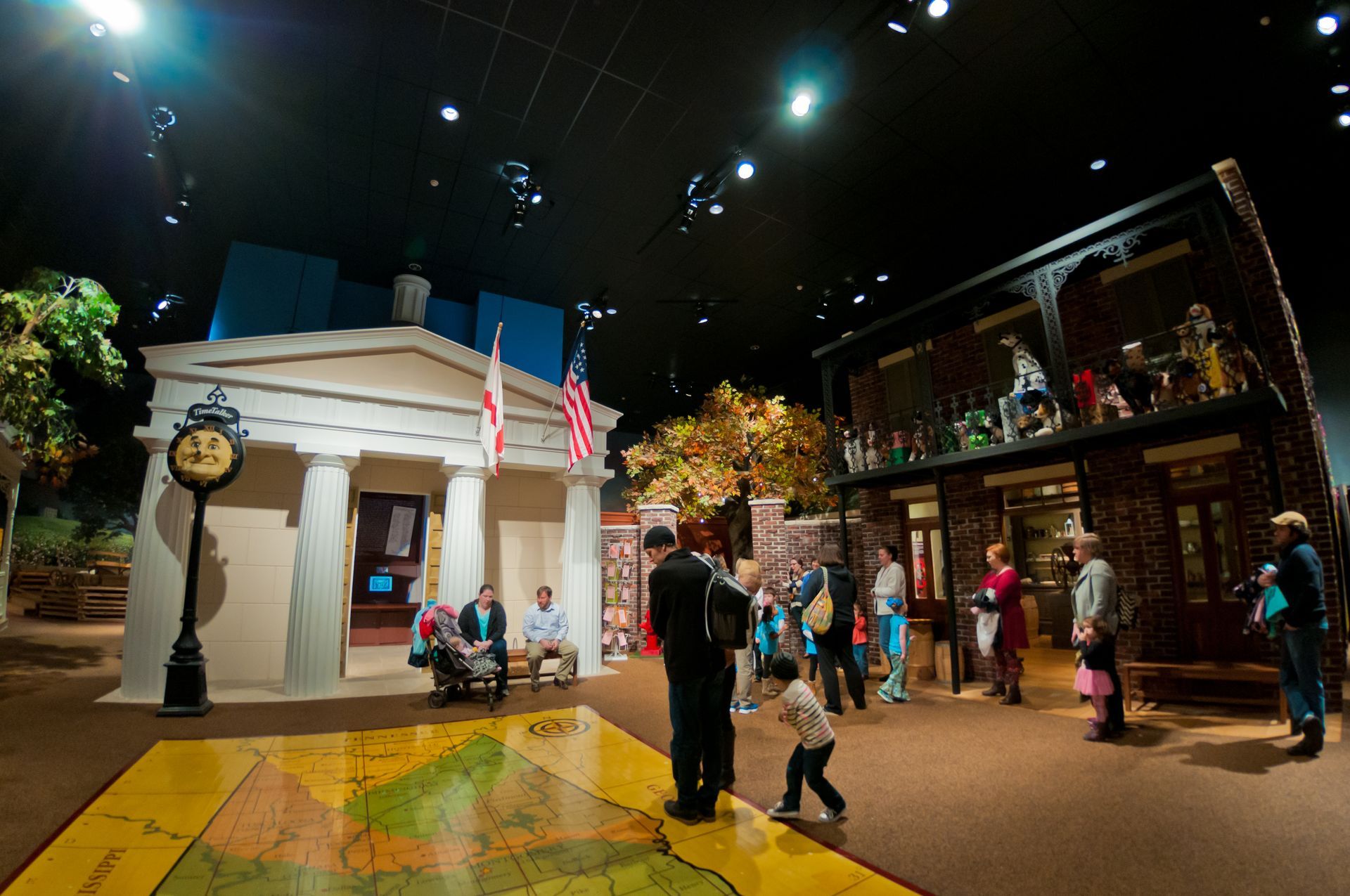 A group of people are standing in a room with a map on the floor.