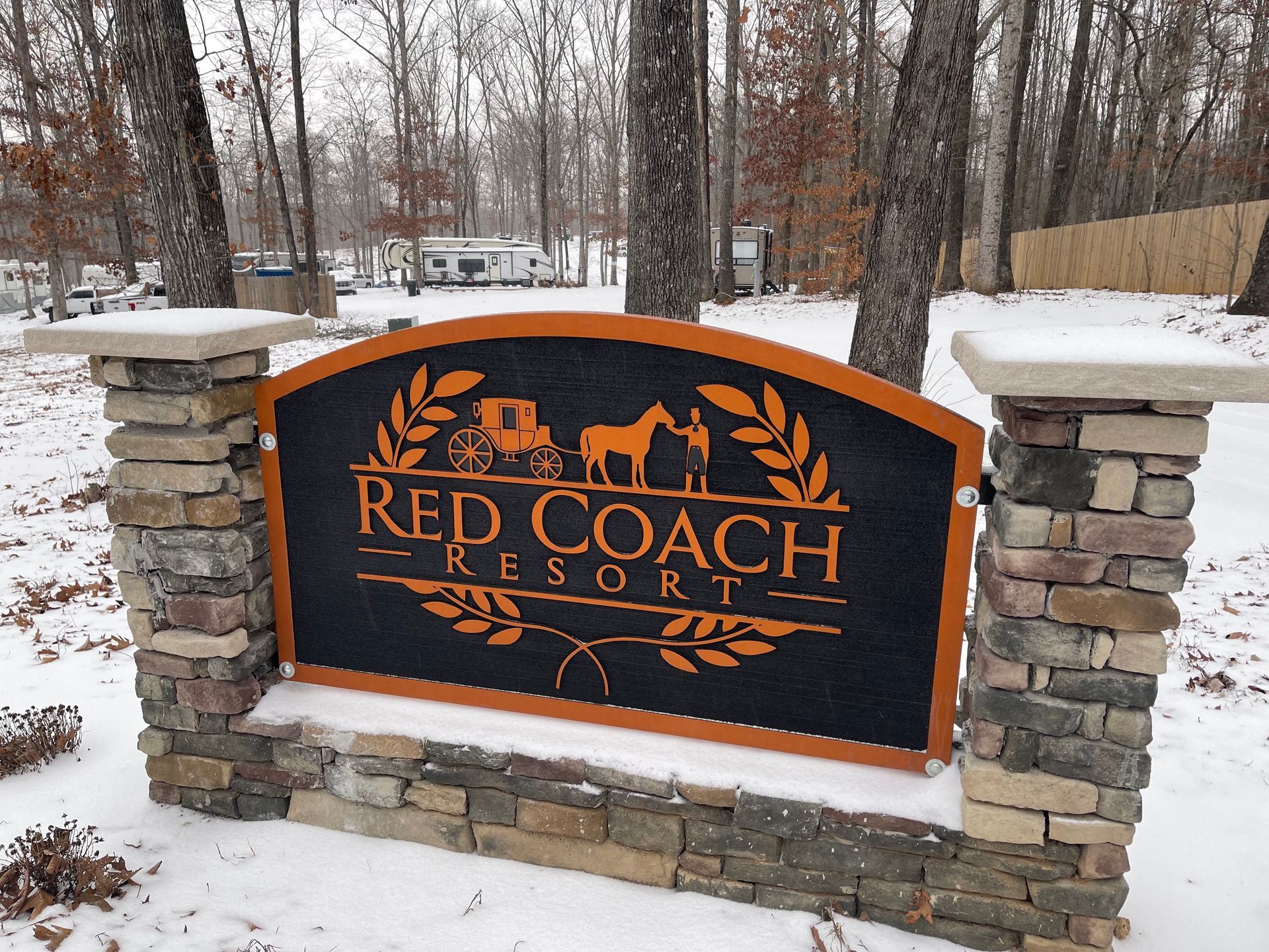 A sign for the red coach resort is surrounded by snow