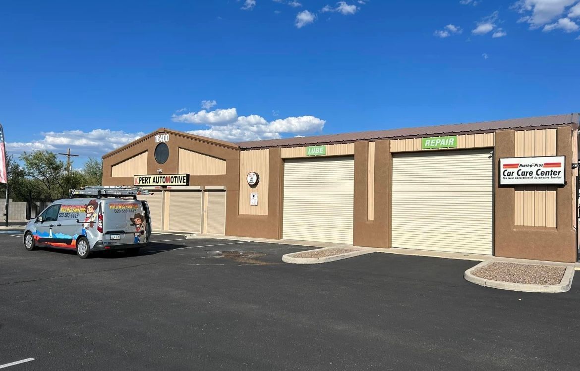 A commercial building with three garage doors, a vehicle parked outside, and a sign that reads 