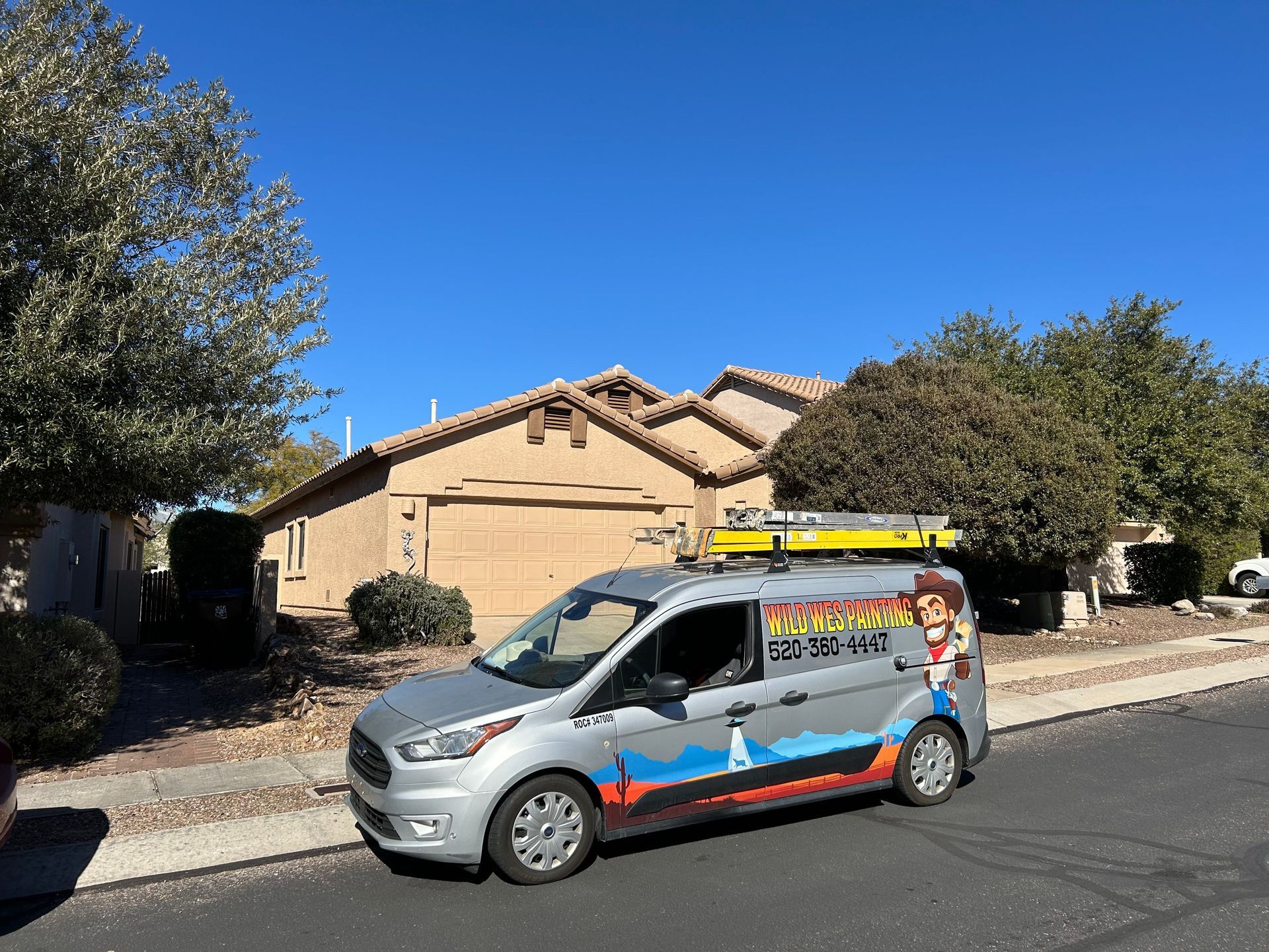 A silver service van parked in front of a house with the company logo displayed on the side.