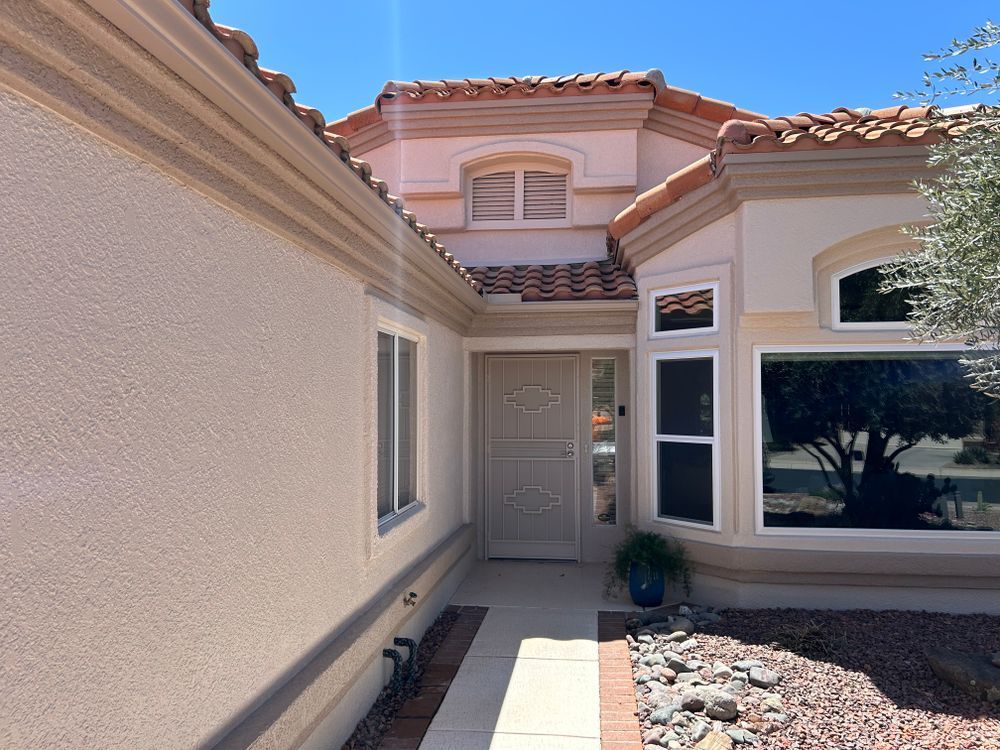 Beige stucco home with a red tile roof and a walkway leading to the front door.