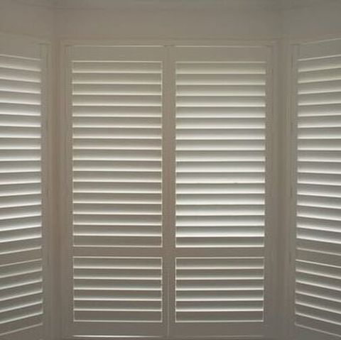 Close up of white closed PVC Plantation Shutters, with light filtering in.