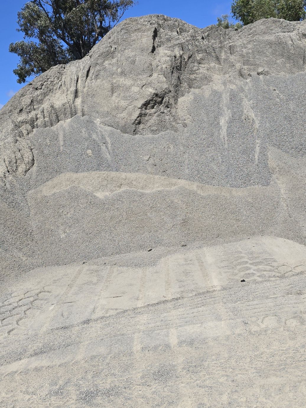 Pile of gray gravel under a blue sky — Coastal Sand Soil & Mulch in Craignish, QLD
