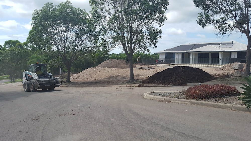 A Skid Steer Loader Works Near Piles of Dirt — Coastal Sand Soil & Mulch in Craignish, QLD
