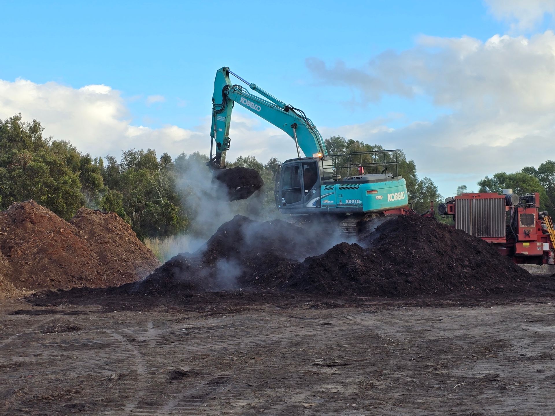 Large Piles of Dark Brown and Reddish-brown Mulch Outdoors — Coastal Sand Soil & Mulch in Craignish, QLD
