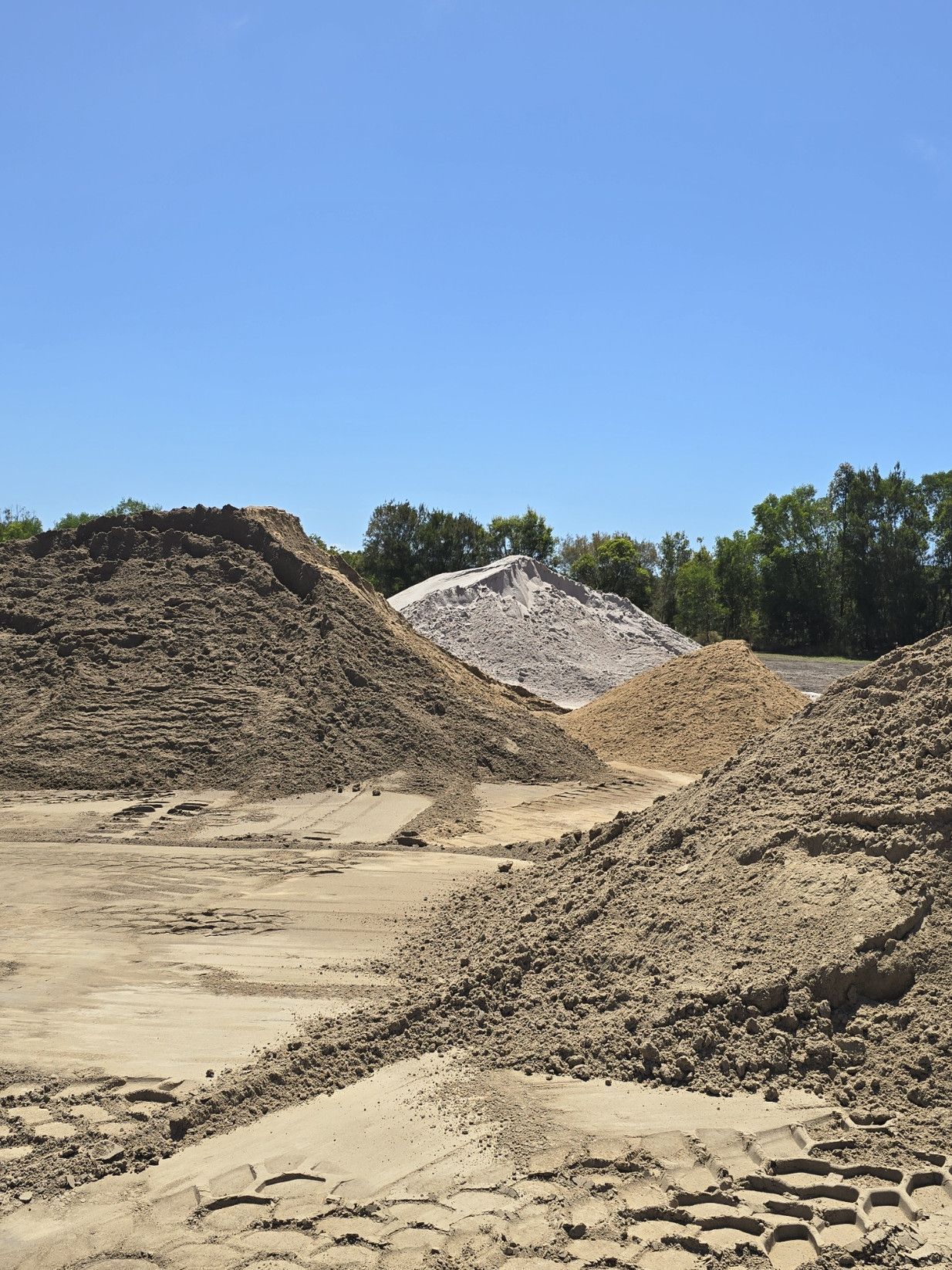 Yellow Front-End Loader  with A Large Pile of Sand Behind It — Coastal Sand Soil & Mulch in Craignish, QLD