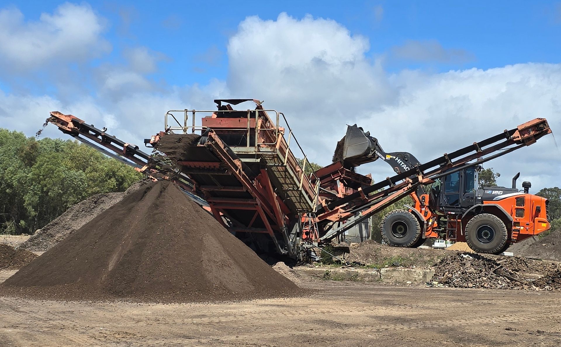 A Large Excavator Digging Into a Soil Pile at A Construction Site — Coastal Sand Soil & Mulch in Urangan, QLD