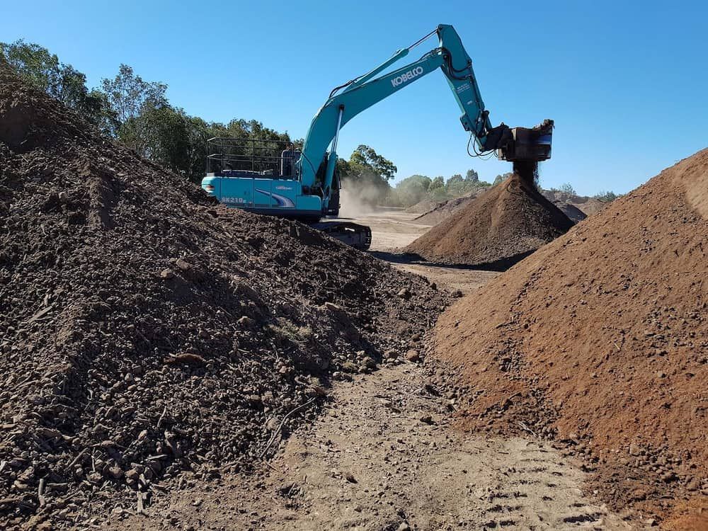 Blue Excavator Moving Soil on a Construction Site on a Sunny Day — Coastal Sand Soil & Mulch in Craignish, QLD