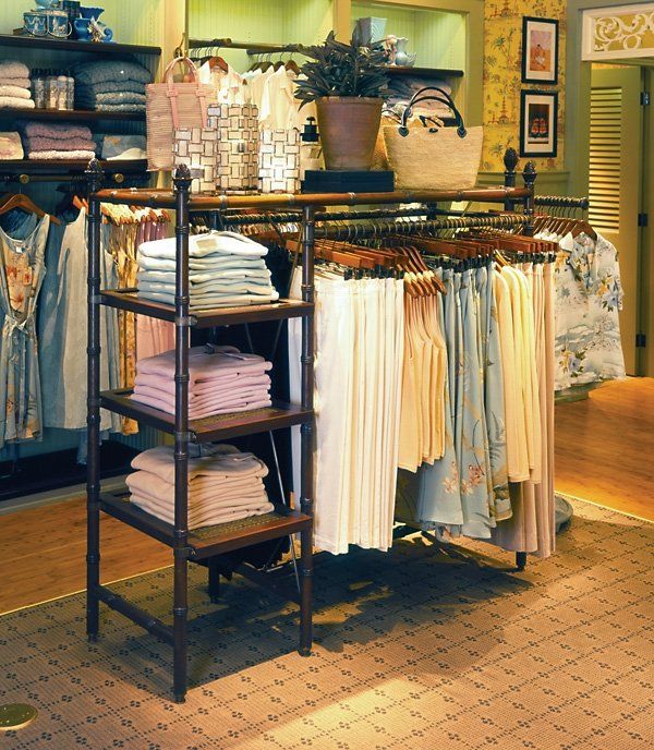 Pro shop display featuring a dark brown rack with folded shirts and hanging garments in various colors.