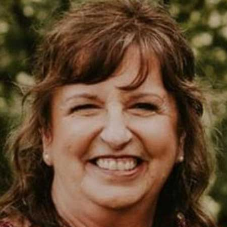 A young man in a white shirt is smiling in the desert.