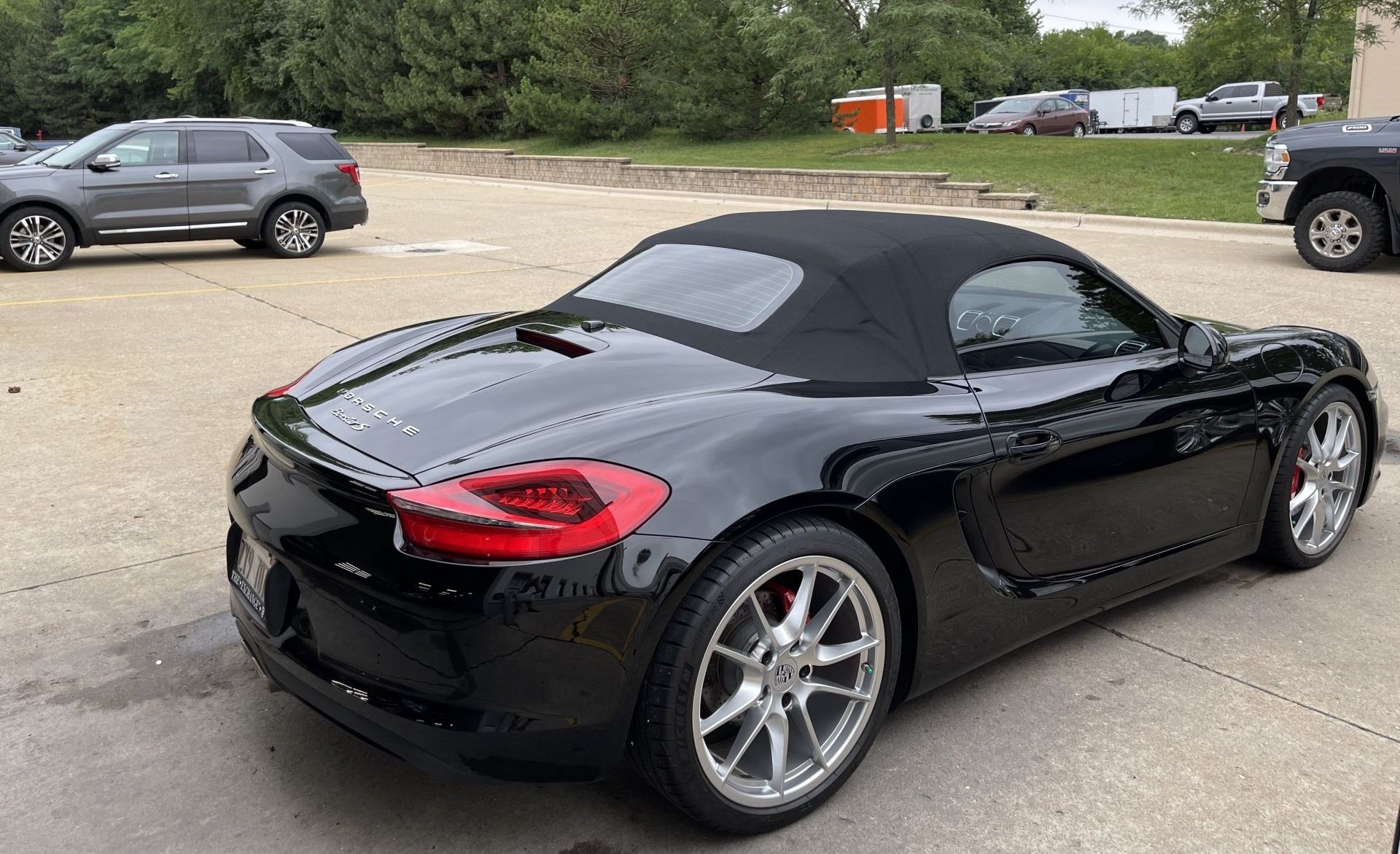 A black convertible sports car is parked in a parking lot.