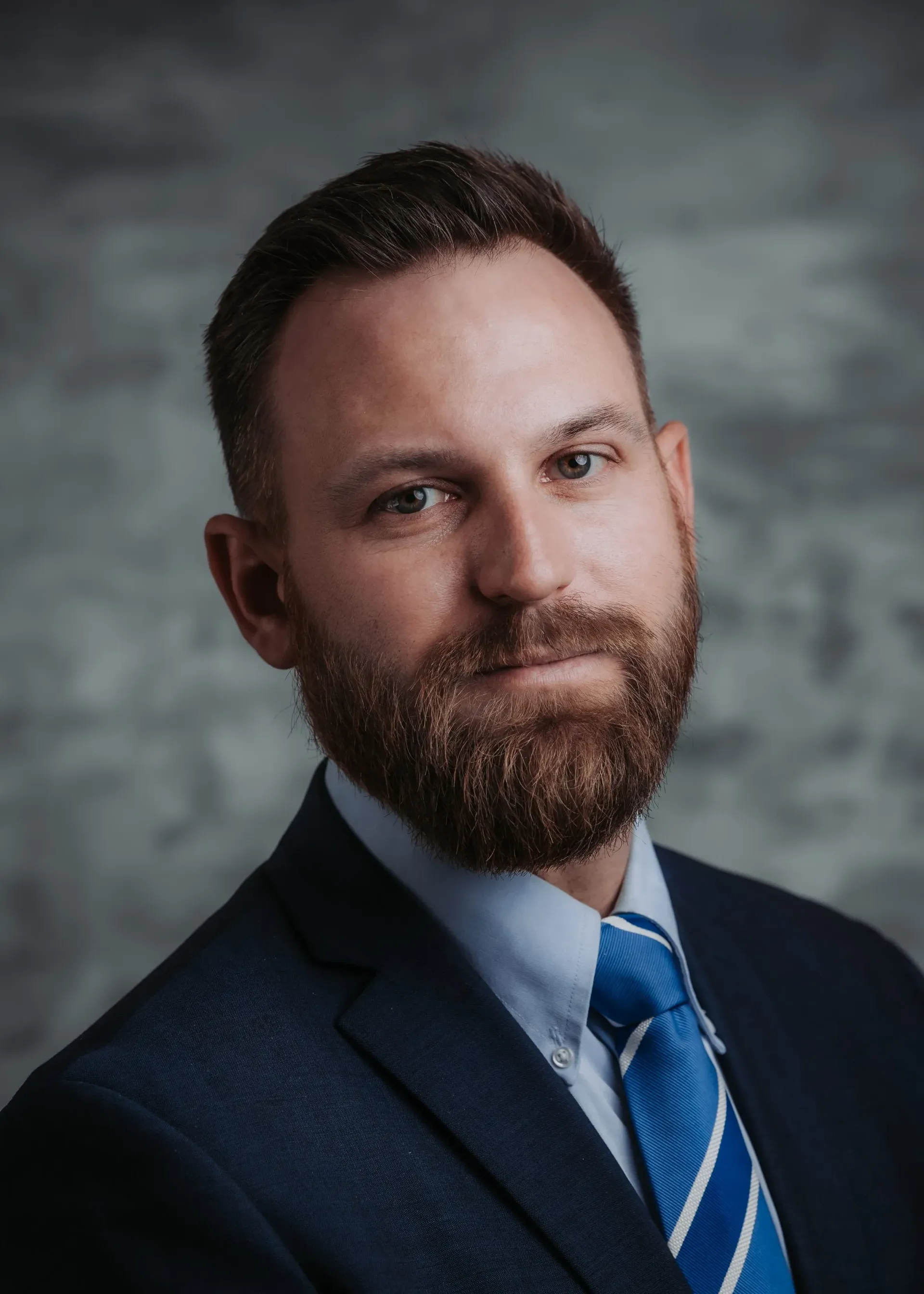 Woman with dark hair, smiling, in a floral shirt, seated indoors with a framed artwork in the background.