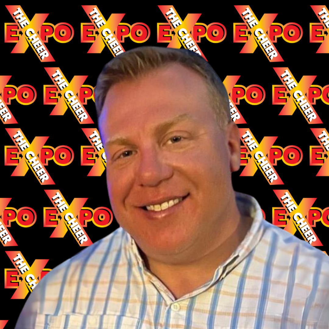 A man is smiling in front of a sign that says the expo