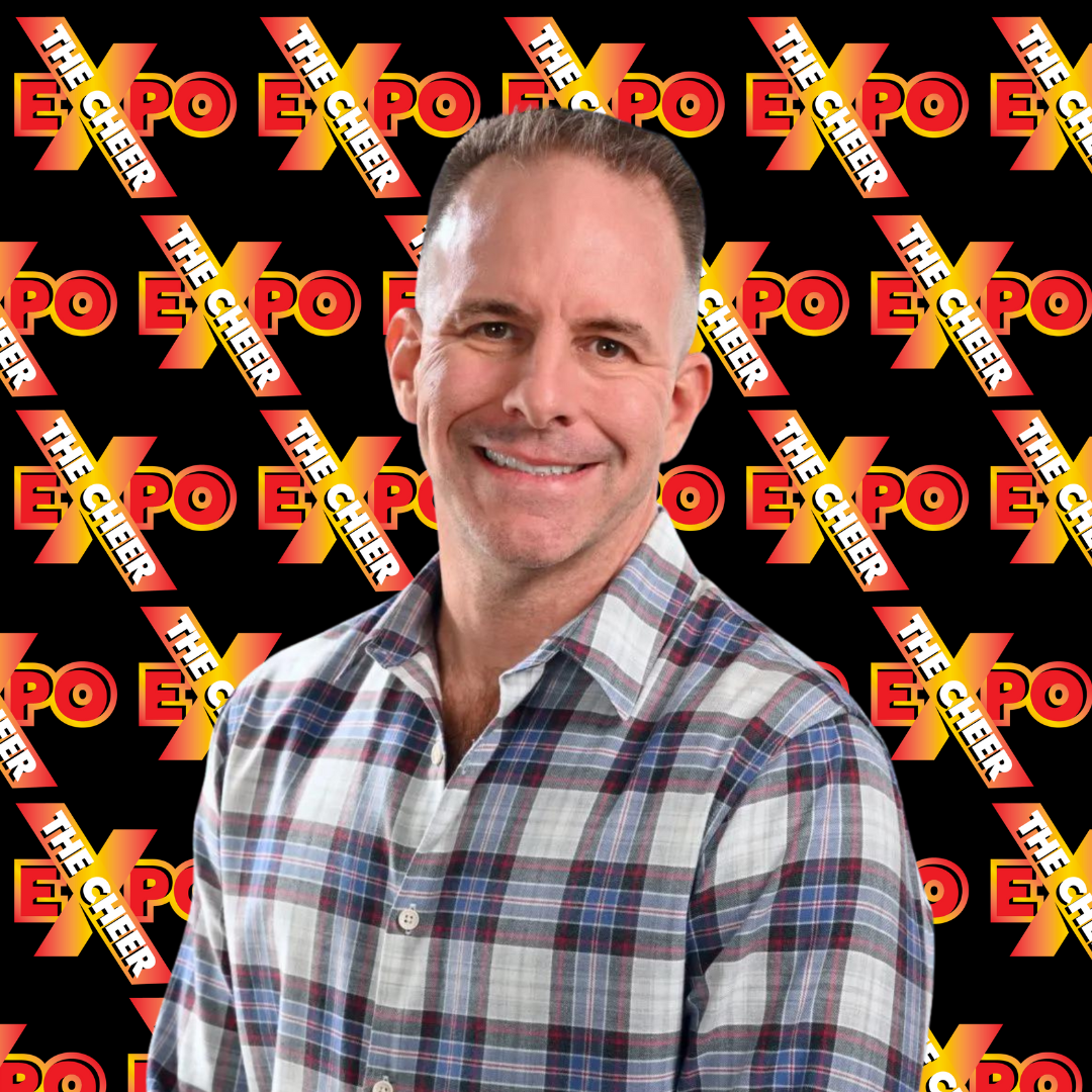 A man in a plaid shirt is smiling in front of a black background with the word expo on it