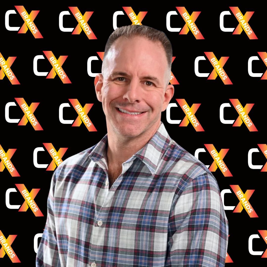 A man in a plaid shirt is smiling in front of a black background with the word expo on it