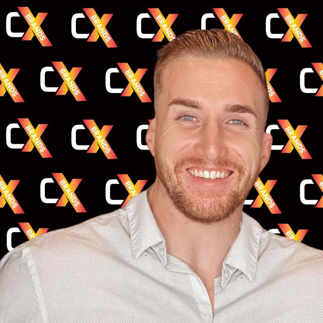 A man with a beard is smiling in front of a sign that says the expo
