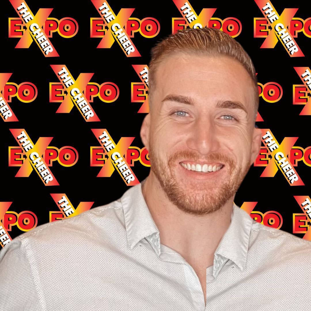 A man with a beard is smiling in front of a sign that says the expo