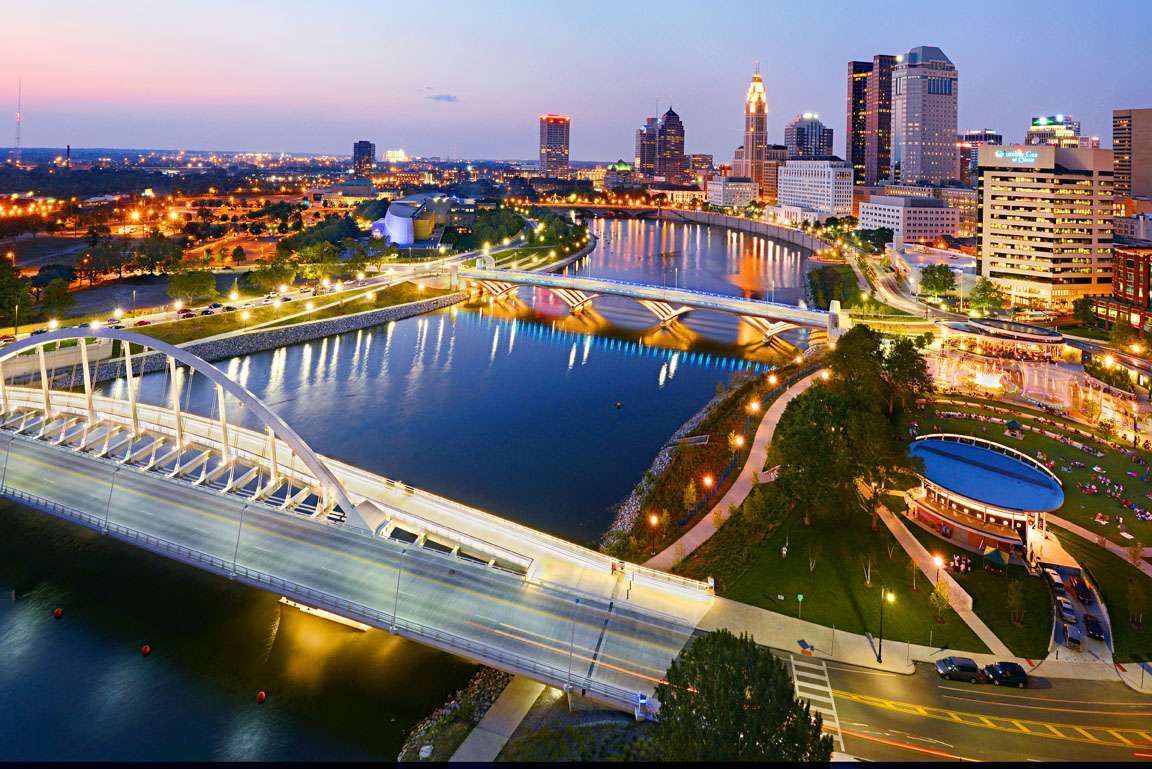 An aerial view of a bridge over a river in a city at night.