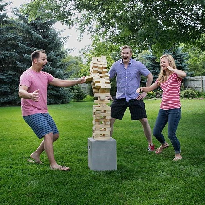 A group of people are playing a game of jenga in a backyard.