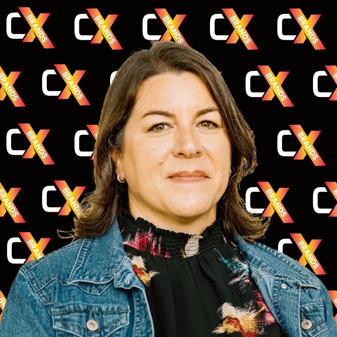 A woman in a denim jacket is smiling in front of a black background with the word expo on it.