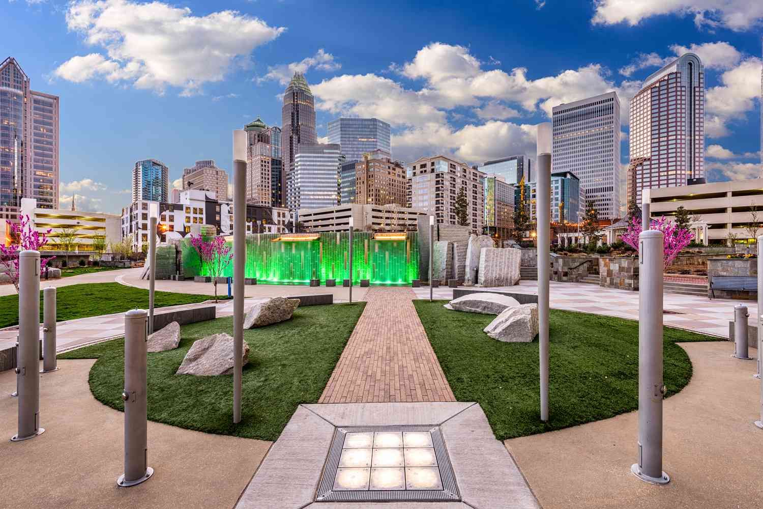 A park with a fountain and a city skyline in the background.